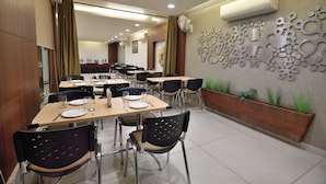 Un comedor con varias mesas y sillas, un equipo de aire acondicionado y decoración en las paredes.