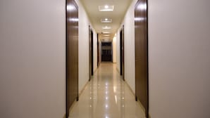Un largo pasillo estrecho con puertas de madera a ambos lados y un suelo de baldosas brillantes.