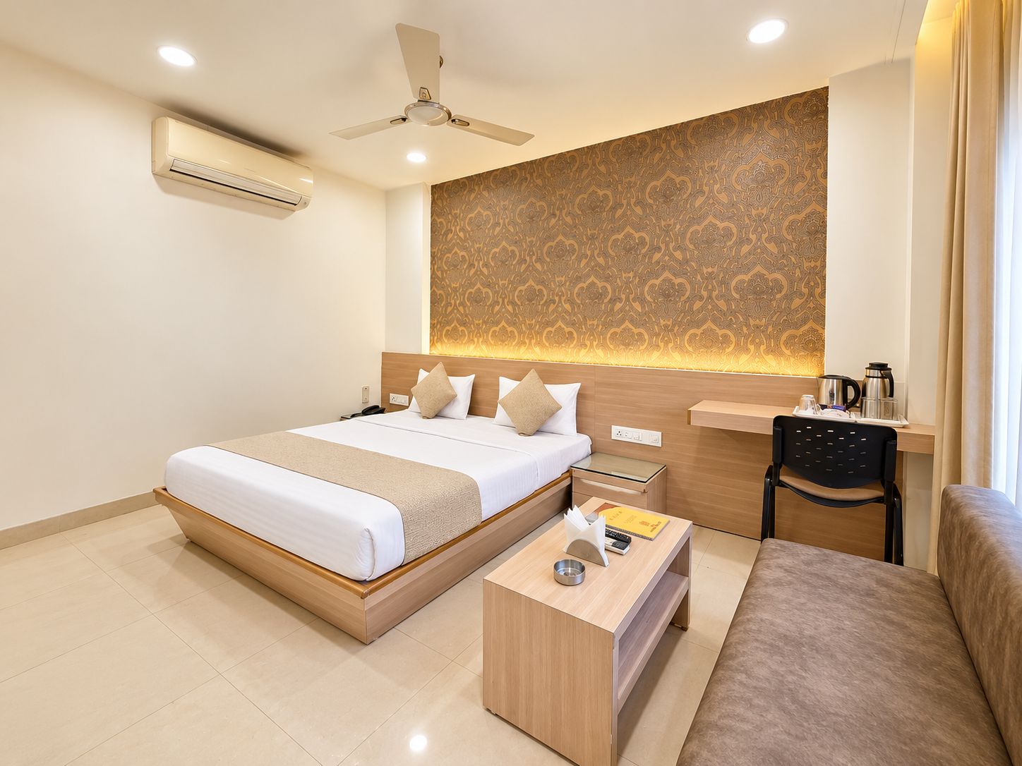 Quarto de hotel com cama, mesa de cabeceira, cadeira e escrivaninha com cadeira.