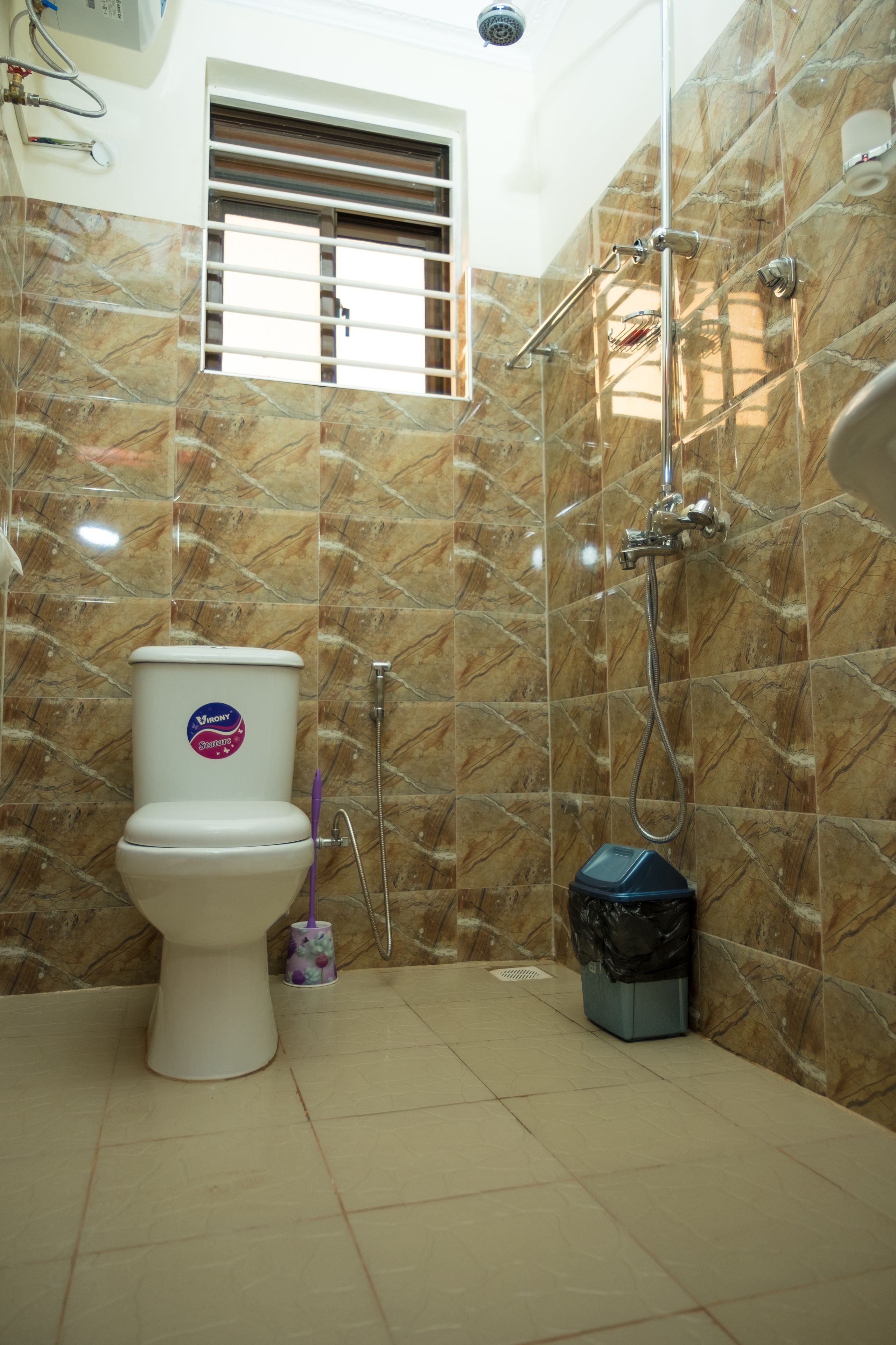 Ein Badezimmer mit Toilette, Dusche und einem Mülleimer.