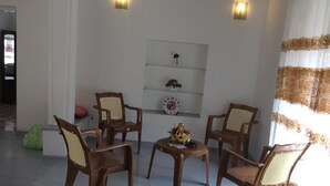 Ein Wohnzimmer mit vier Holzstühlen, einem kleinen Tisch und einer Wanduhr.