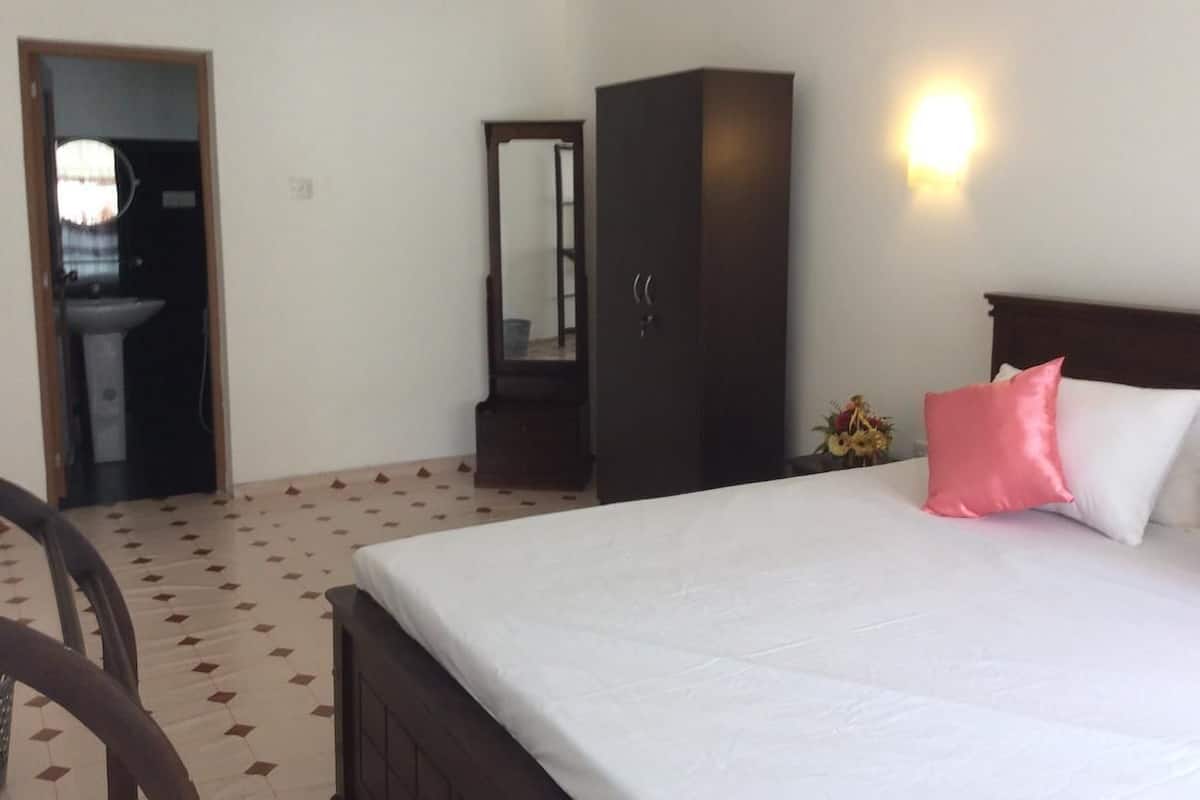 Una habitación de hotel con una cama, un armario, un espejo, un lavabo y una lámpara fijada a la pared.