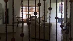 Ein Zimmer mit einer Couch, Stühlen und einem Tisch. Vorhänge und ein Fenster mit Blick.