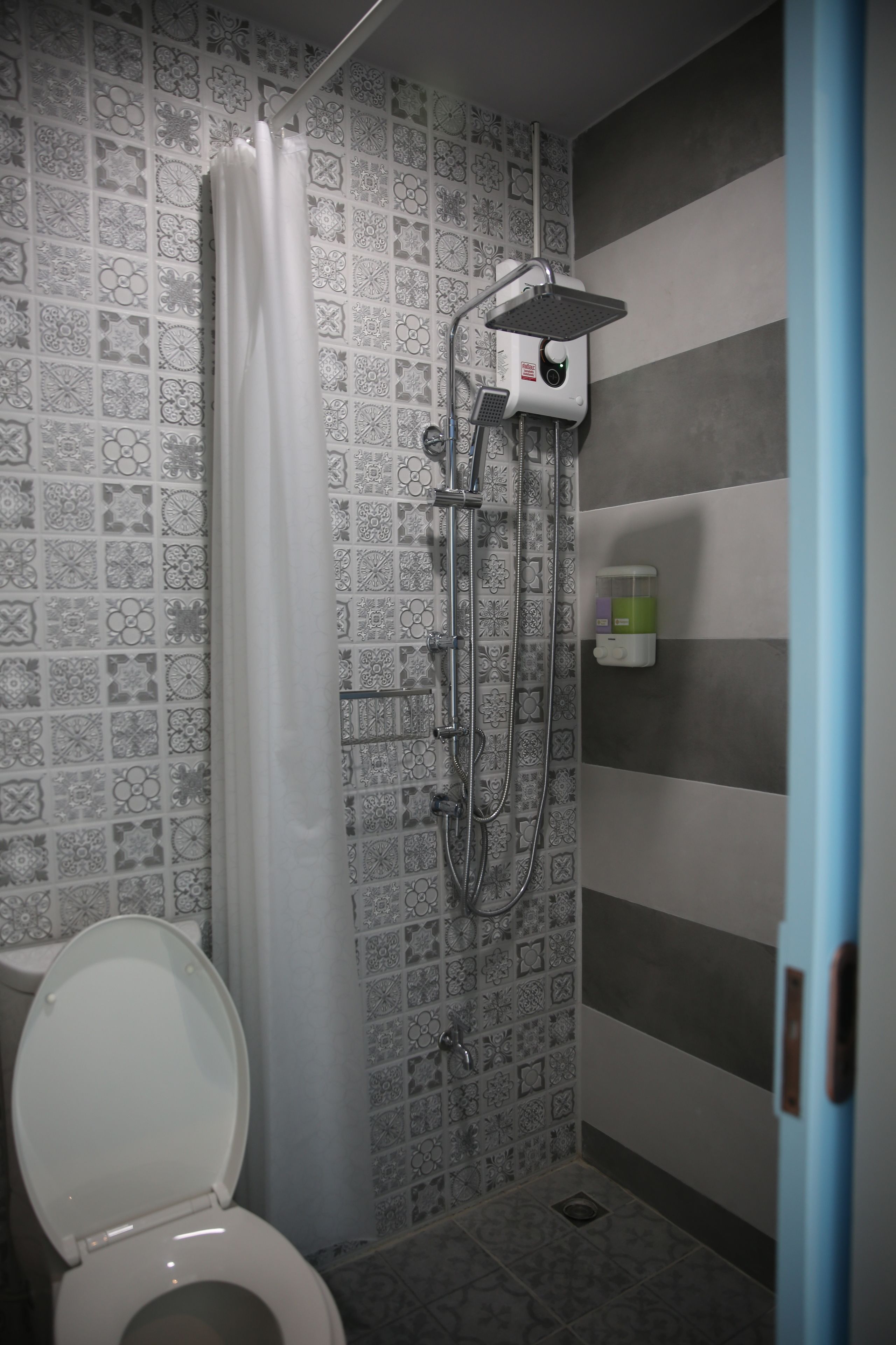 A bathroom with a shower, toilet, and patterned tiles.