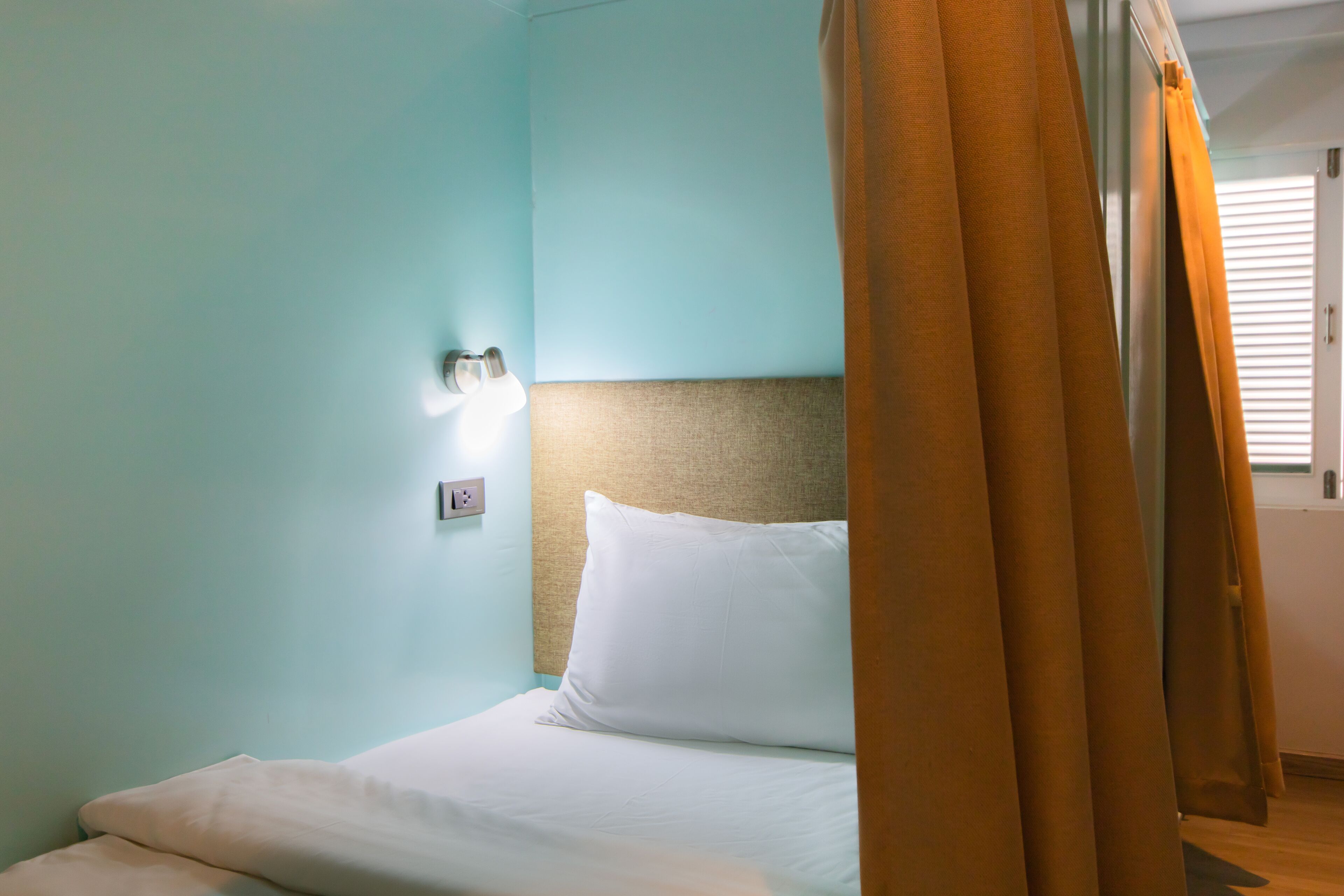 A hotel room with a bed, a headboard, and curtains.