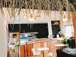 A modern interior with wooden paneling, white chairs, a bar area, and hanging plants.