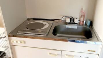 Una kitchenette compacta con estufa integrada, pileta y una pequeña mesada.
