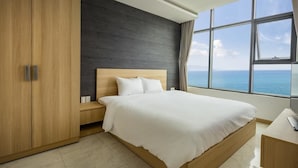 A modern bedroom with a large bed, wooden wardrobe, and a view of the sea. - Ideal Time Apartment (Nha Trang)