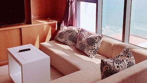 A modern living room with a sofa, a coffee table, and a TV on a wooden stand. - Ideal Time Apartment (Nha Trang)