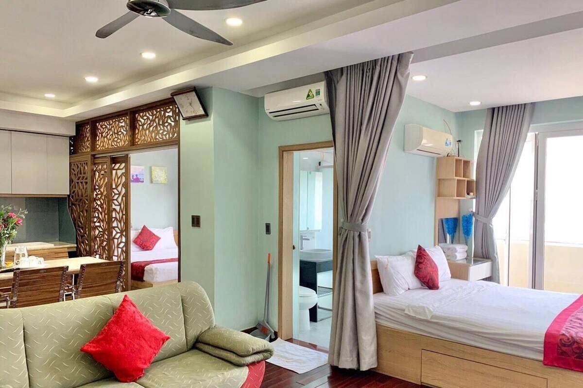 A hotel room with a bed, a sofa, a dining area, and a bathroom.