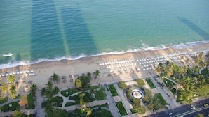 An aerial view of a beach with rows of umbrellas and palm trees. - Ideal Time Apartment (Nha Trang)