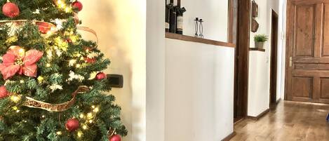 A hallway with a Christmas tree, a wine rack, and a wooden door.