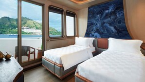 A room with two beds, a view of a body of water, and a decorative wall. - AYANA Lako di'a (Labuan Bajo)