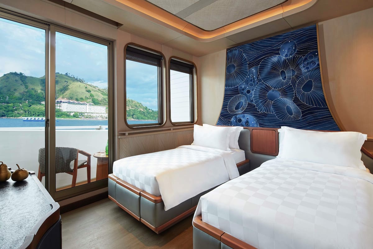 Ein Zimmer mit zwei Betten, Blick auf ein Gewässer und einer Wandverkleidung.