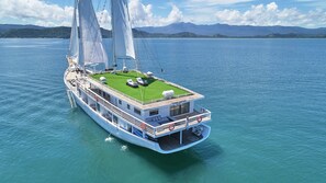 A yacht with a green deck area, multiple decks, and a name 'AYANA LAKO DIA BENOA' on the front. - AYANA Lako di'a (Labuan Bajo)