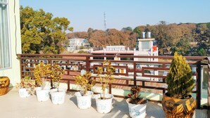 Varanda com vasos de plantas e vista para edifícios e árvores.