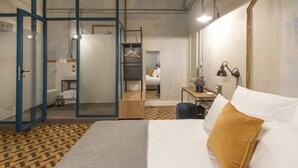 Una habitación de hotel moderna con una cama, un escritorio y un baño visible a través de una puerta abierta.