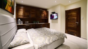 A bedroom with a large bed, wooden cabinets, a TV, and a door. - Garden Residence (Eilat)