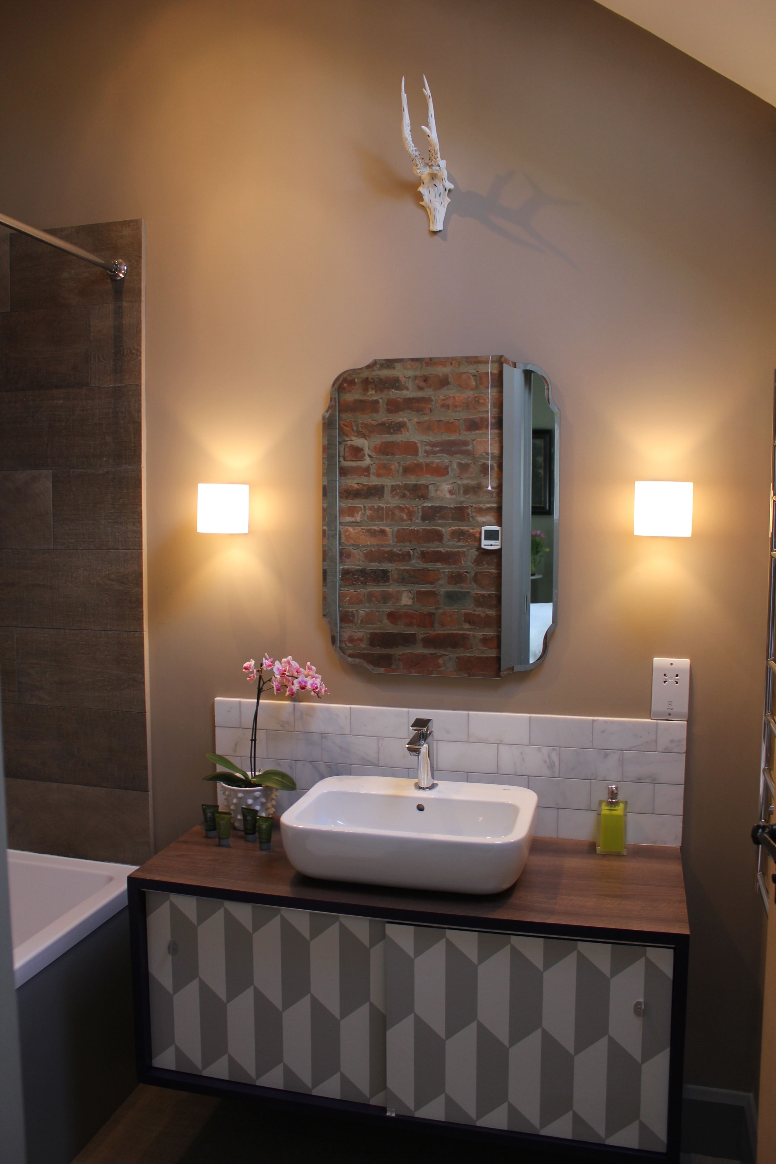A bathroom with a large mirror, a sink, and a shower.