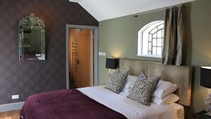 Een slaapkamer met een groot bed, een spiegel, een raam met gordijnen en een deur.