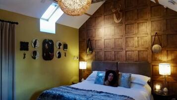 Cozy bedroom with a sloped ceiling and exposed beams, featuring a large bed and decorative items.