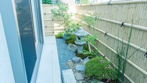 A narrow pathway with a bamboo fence, stepping stones, and a small rock garden with a stone lantern. - Heartwarming House (Kyoto)