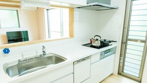 A modern kitchen with a stainless steel sink, a stove, and a dishwasher. - Heartwarming House (Kyoto)