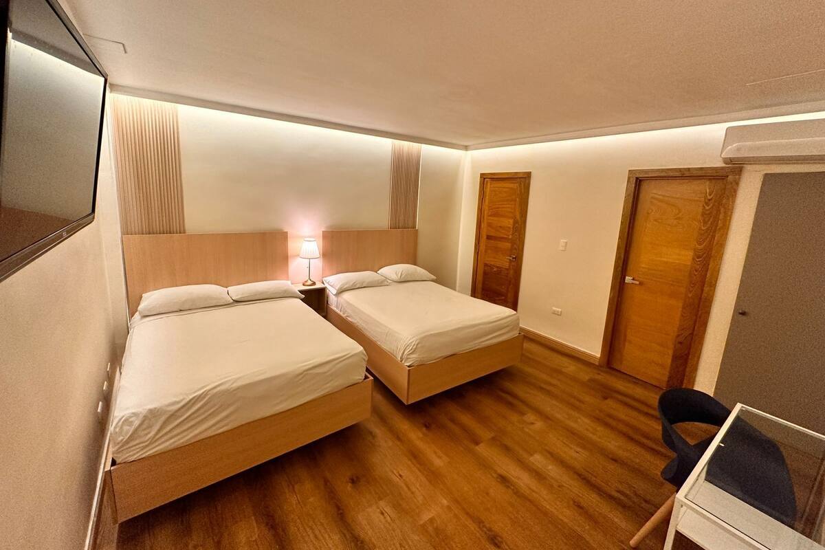A hotel room with two beds, a desk, and a chair.