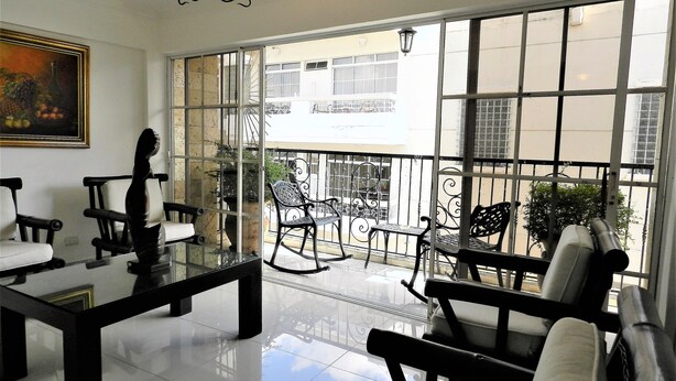 A spacious room with a large window, a chandelier, and a painting on the wall.