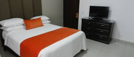 A hotel room with a bed, a television on a dresser, and a door with a sign.