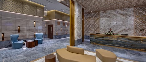 A modern lobby with a reception desk, seating area, and decorative elements.