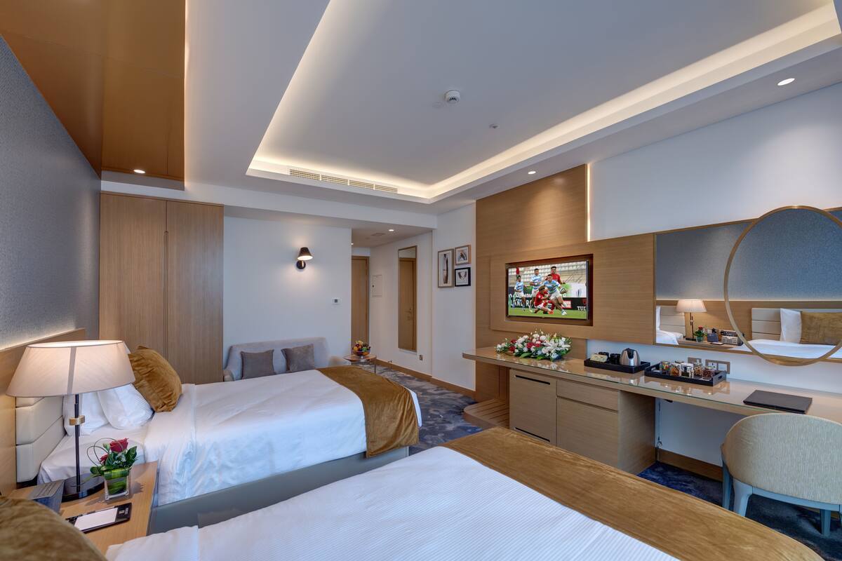 Ein Hotelzimmer mit zwei Betten, einem Schreibtisch, einer kleinen Küchenzeile und einem Badezimmer.