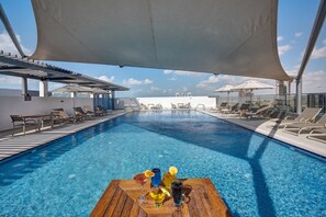 Una piscina al aire libre, sombrillas, tumbonas