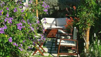 A garden with a wooden pergola, a white outdoor sofa, and a wooden chair.
