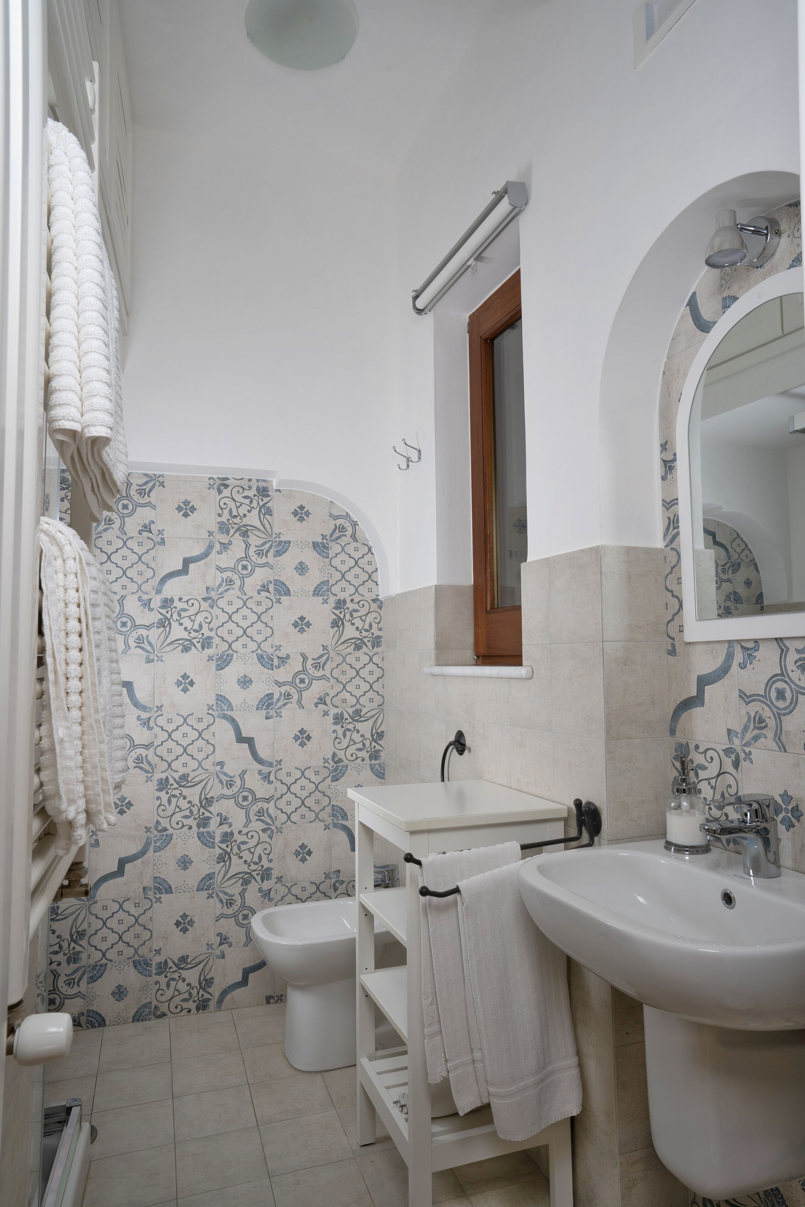 Une salle de bain avec un lavabo blanc, un miroir et des toilettes.