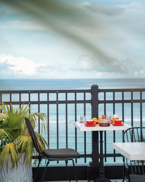 Un balcón con una mesa lista para el desayuno, con vista al mar.
