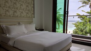 Ein Schlafzimmer mit einem großen Bett, einem Nachttisch und Meerblick durch ein Fenster.