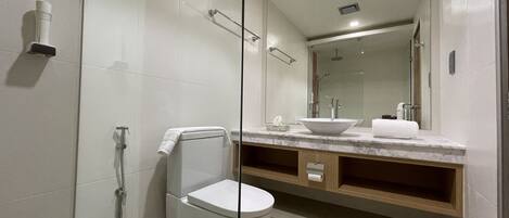 A modern bathroom with a glass-enclosed shower, a white toilet, a marble sink, and a large mirror.