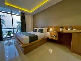 Una camera d'hotel con un letto, un comodino, una lampada e vista sull'oceano.