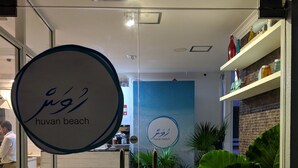 Ein sauberes, modernes Interieur mit einer Rezeption, einer blauen Wand mit einem Logo und Topfpflanzen.