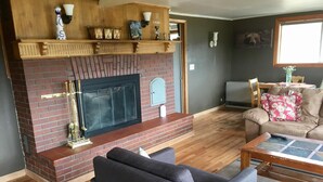 A living room with a brick fireplace, a sofa, a coffee table, and a television. - Timberline Inn of Grand Lake (Grand Lake)