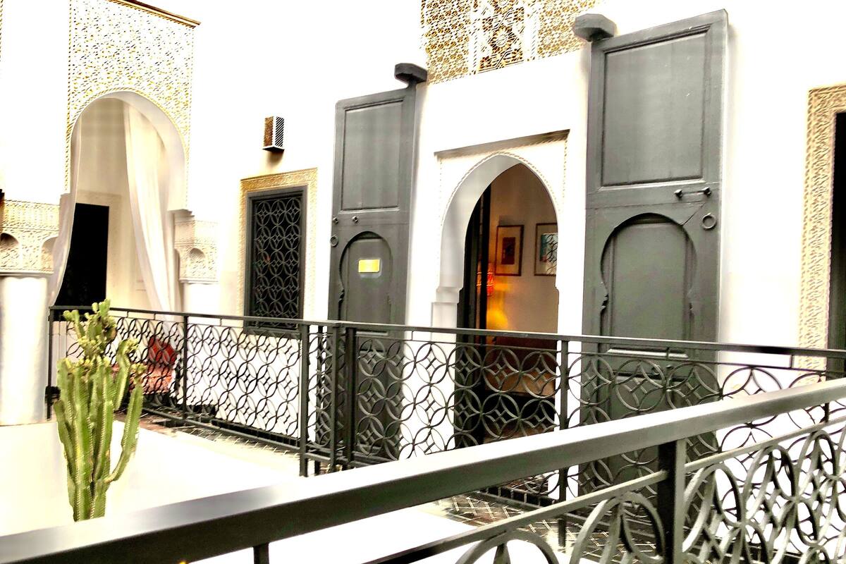 A courtyard with a metal railing, a cactus plant, and a door with a small sign.