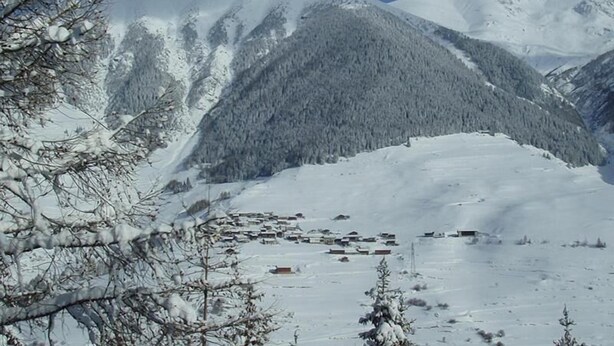 A snow-covered mountain landscape with a small settlement in the valley. - Hôtel Terminus (Orsieres)