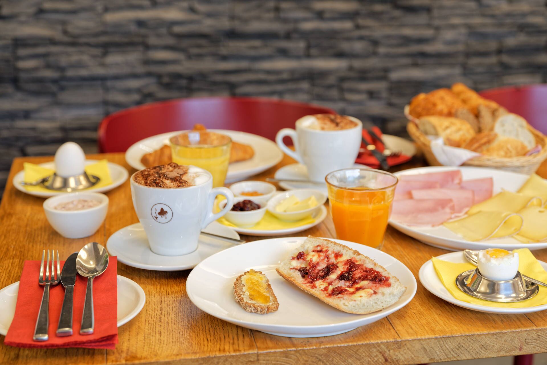 Un desayuno con diversos platos, como tostadas, huevos y zumo de naranja.