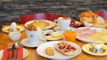 Un desayuno con diversos platos, como tostadas, huevos y zumo de naranja.