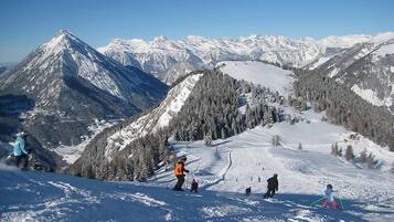 A snowy mountain landscape with skiers and snowboarders.