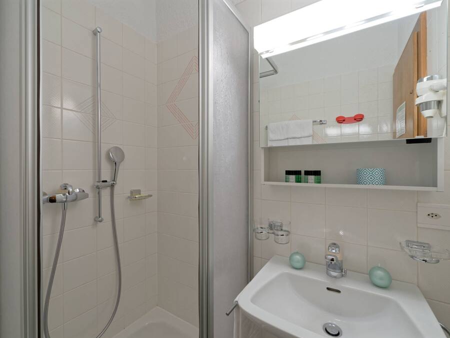 A bathroom with a shower, a sink, and a mirror.