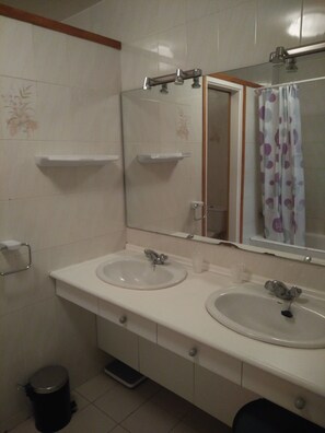 A bathroom with two sinks, a mirror, and a shower curtain.