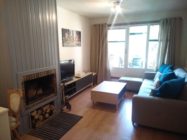 A living room with a fireplace, a sofa, a coffee table, and a television.