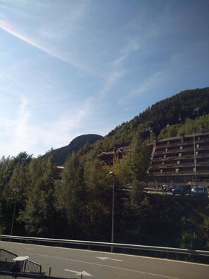 A multi-story building with balconies, surrounded by dense forest and hills.